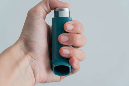 Human hand picking up an asthma inhalerの写真素材