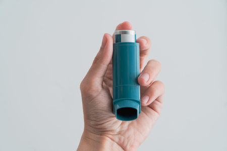Human hand picking up an asthma inhalerの写真素材