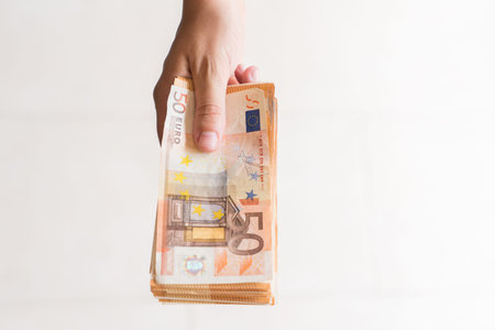 Woman hand holding a lot of 50-euro notes for paying on white background