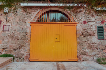 Ancient yellow wooden door on a stone wall in Calella de Palafrugell village.の写真素材