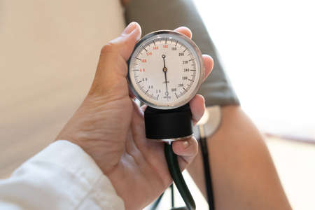 Doctor measuring blood pressure of a young womanの写真素材