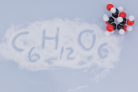 Isolated glucose molecule made by molecular model with glucose formula written on white sugar. C6H12O6 sugar chemical formula with colored atoms and bondsの写真素材