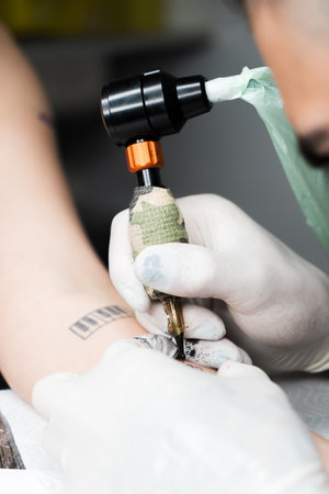 Tattooist makes a tattoo on the arm of a manの写真素材