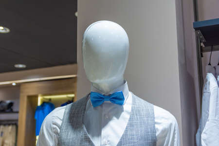 White mannequin in a store with gray vest and blue bow tie.の写真素材