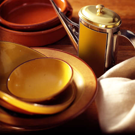 Old olive oil can next to bowls and platesの写真素材