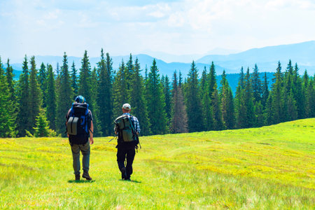 Two friends travel in mountains with backpacks