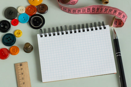 Sewing supplies - thimble, needle, measuring tape, spools of thread notepad and pen for taking notes