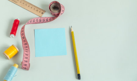 Background for sewing. Needlework supplies on a light background. Spools of thread, scissors, buttons, measuring tape, sewing accessories. notebookの写真素材