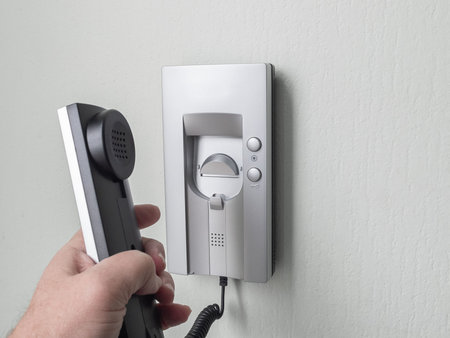 Men hand picks up intercom receiver in apartment