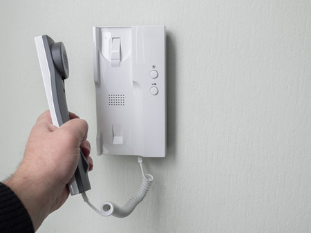 Hand picks up intercom receiver in apartment