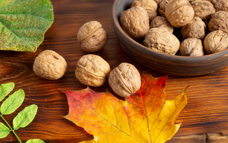 Walnuts in the bowl, on the table and fall maple leaves