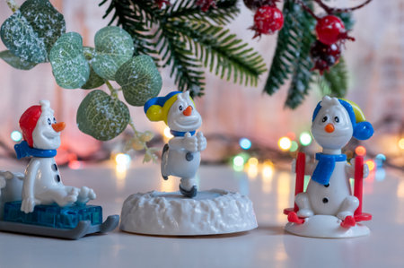 New Year figures of sledges and snowmen on the background of Christmas tree branch and garlandの写真素材