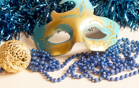 Beads and tinsel for new year mask on light background. New Year decoration with a maskの写真素材