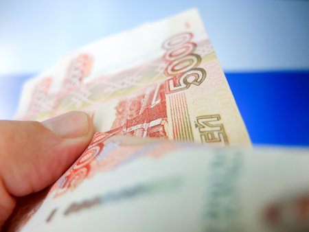 Russian banknotes in hand close-up. National flag in the backgroundの写真素材
