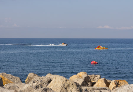 A boat and jet skis are floating on the sea.の写真素材