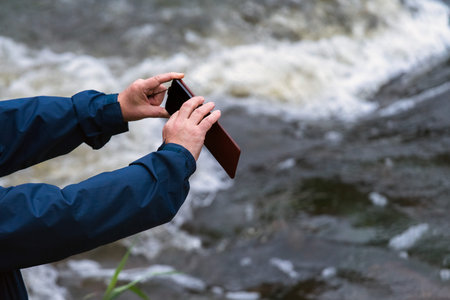 Old man hands holding a phone. Senior man with smart phone taking pictures outdoorsの写真素材