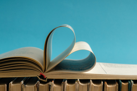 Old hard cover book page decorate to heart shape for love in valentine day with blurred background and vintage style. Composition of love, learning, studying and school.の写真素材