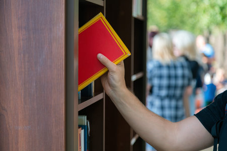 young man searching for a book in bookstore. university student selecting a book in bookshelf library. male college student, education research and self learning in university life conceptsの写真素材