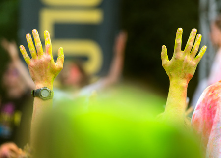 Young mans hands in the air in a color fest with yellow dust. Fun and joyful colour festival moment.  Young people enjoying time together. Youth friendship concept with multicolored dust powder gamesの写真素材