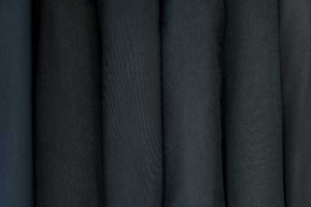 Different clothing textures of fine cloth at a tailor shop. Clothing design. Dark, black suitsの写真素材