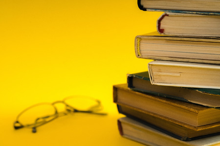 Open book, hardback hard cover colorful books with reading glasses on the side. Back to school. Copy space for text. Education, studying, learning, business conceptの写真素材