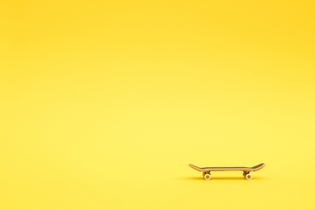 Fingerboard. A small skateboard for kids and teenagers to play with hand fingers. Isolated on yellow background with space for typeの写真素材