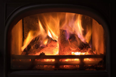 Burning fireplace with wooden logs burning inside. Warm light, romantic, christmas like atmosphere