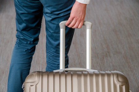 Close up of young business man with suitcase luggage on the carpet at the airport hallの写真素材