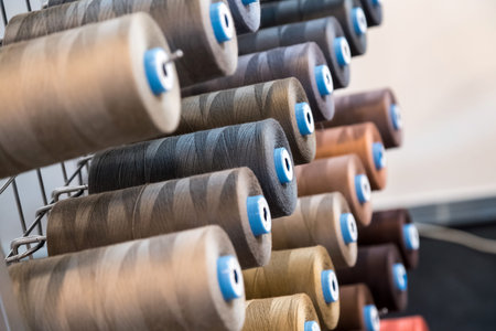 Colorful embroidery thread spool using in garment industry, row of multicolored yarn rolls, sewing...