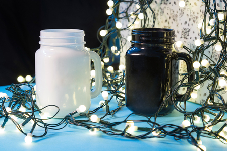 His and Hers personalised tea cups on white background, mugs, Christmas gift ideas, gifts wrapped with Christmas tree lightsの写真素材