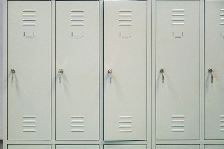 A row of grey metal school lockers with keys in the doorsの写真素材