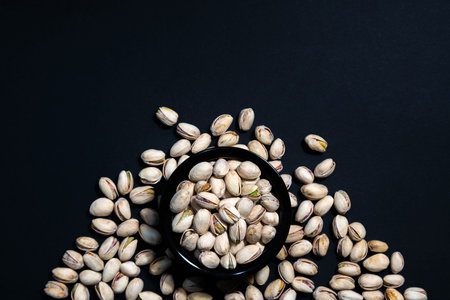 Pistachios nuts in ceramic bowl on wooden table. Food mix background, top view, copy space, banner