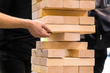 Tower block, man take a wooden part of wooden tower. Planning, risk and strategy in business concept