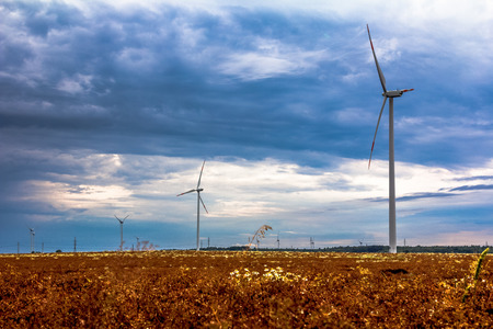 Windmills in the fields with dramatic rain clouds in the backgroundの写真素材