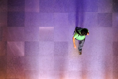 Looking down at silhouette of business man, traveler walking on the marble brick floor. Top view,...