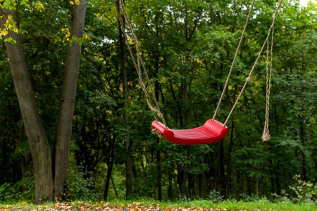 Red swings in between two trees in the woods, fun outdoor activity for kids