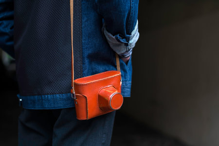 Man in jeans jacket with vintage film camera in a leather case