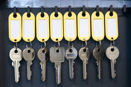Hanging keys in metal cabinet for safety office or household keys management and keeping. keys with blank name tags, space for textの写真素材
