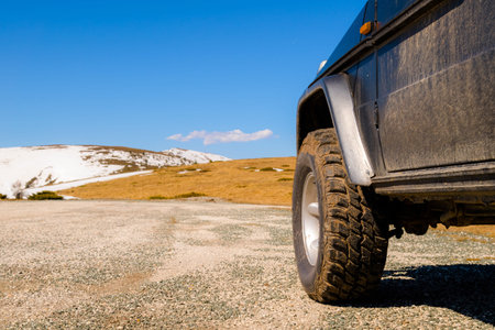 Off road 4x4 car in the snowy mountains on a sunny day. Off-road traveling, all terrain vehicle in...