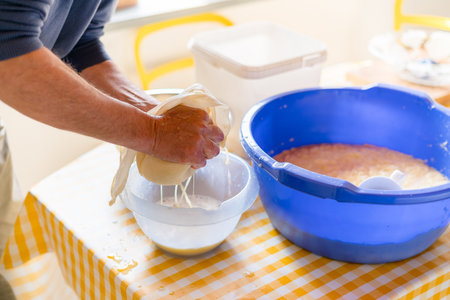 Making of Cepelinai - Zeppelins is national Lithuanian dish. Mans hands draining grated potatoes....