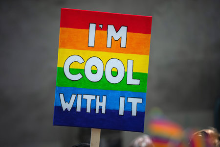 Rainbow flag sign with words supporting LGBT community on gay parade event. Colourful flag banner...