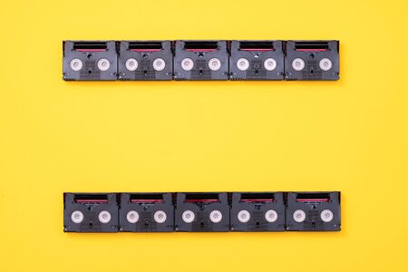 Analog film screen concept made of vintage mini DV cassette tapes used for filming back in a day. Pattern made of plastic video tapes on yellow backgroundの写真素材