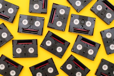 Vintage mini DV cassette tapes used for filming back in a day. Random pattern made of plastic video tapes on yellow backgroundの写真素材