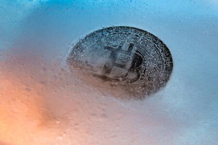 Silver Bitcoin, bit coin online digital currency frozen in the blue ice. Concept of block chain, crypto market crash. Frozen crypto money, depreciationの写真素材