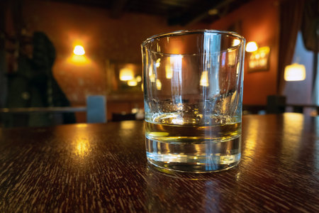 Drinking whiskey in an empty bar. Golden colour alcohol drink on wooden table in a pub. Relaxing...