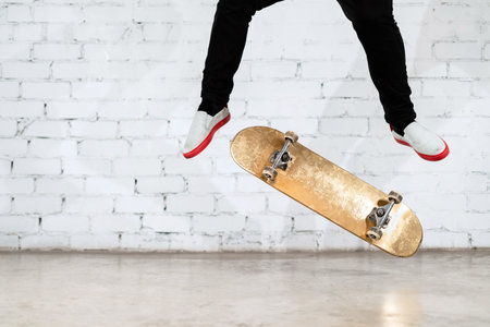 Skateboarder performing skateboard trick - kick flip on concrete. athlete practicing jump on white...
