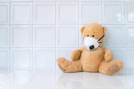 Teddy bear with face mask on white background. Concept of home school, isolation. Staying at home. Corona virus.の写真素材