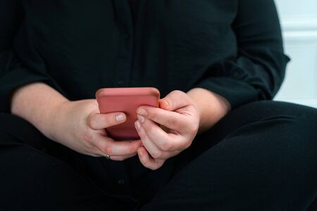 Close up of woman reading news on smart phone at home. Hands texting message or scrolling on social media. Browsing internet, chatting onlineの写真素材