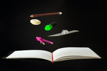 Levitating school supplies for math - notebook, pen, ruler, pencil, divider and eraser on black...
