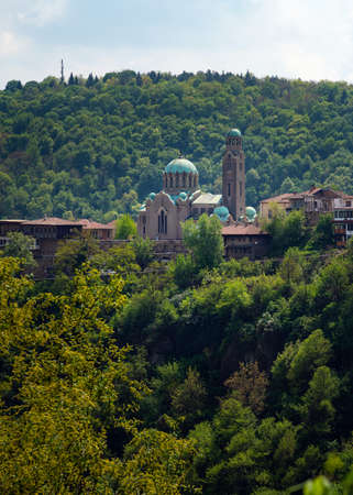 St Demetrius orthodox cathedral in Veliko Tarnovo city, Bulgaria. Tourist attraction surrounded by trees and mountain.のeditorial素材